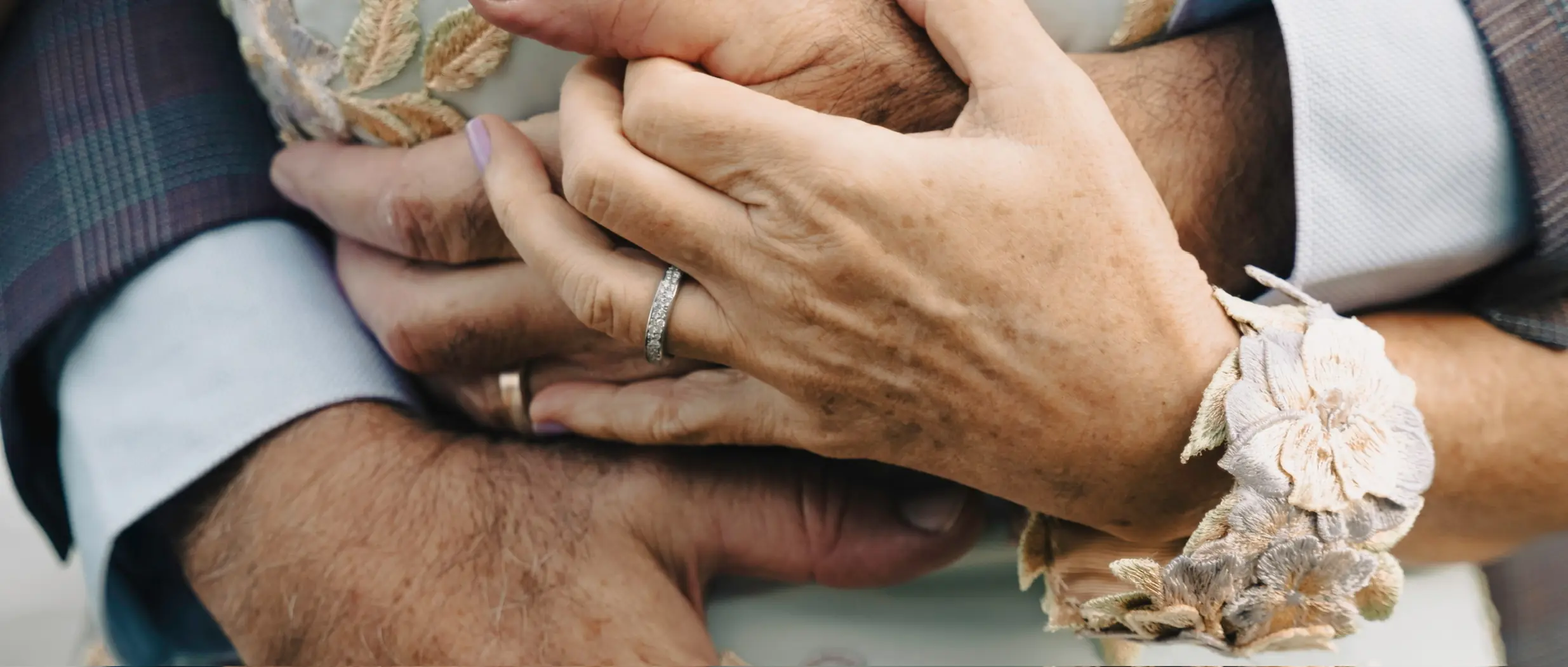 Close-up of an older couple's clasped hands and wedding rings